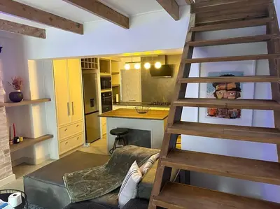 a living room with a wooden ladder and a kitchen at Lemon House Modern duplex by UCT in Cape Town