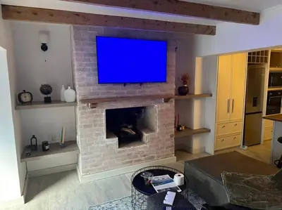 a living room with a tv on a brick fireplace at Lemon House Modern duplex by UCT in Cape Town