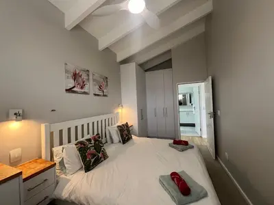 a bedroom with a white bed with a white ceiling at Sunset Starfish Apartment in Cape Town
