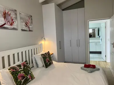 a bedroom with a white bed with two pillows at Sunset Starfish Apartment in Cape Town