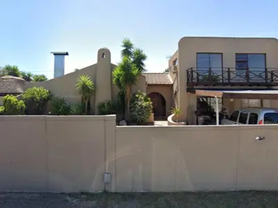 a fence in front of a house with palm trees at Gizelle in Cape Town
