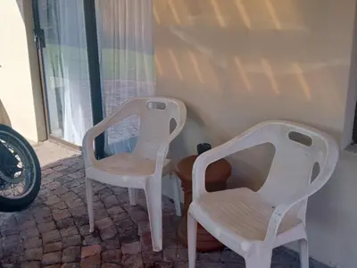 two white chairs sitting next to a wall at Gizelle in Cape Town