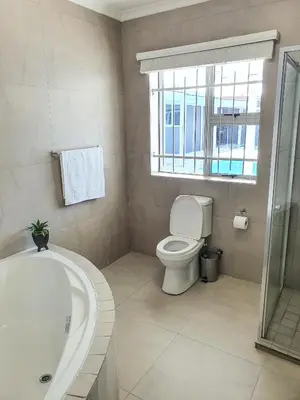 a bathroom with a tub and a toilet and a window at Howards Villas in Cape Town