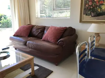 a brown leather couch in a living room with a table at Tolbos Garden in Cape Town