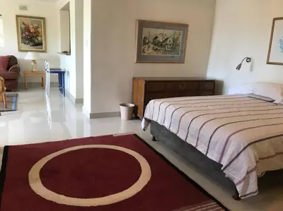 a bedroom with a large bed and a red rug at Tolbos Garden in Cape Town