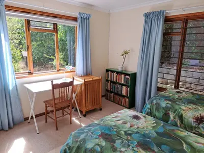a bedroom with two beds and a desk and a table at Helderberg Cottage in Somerset West