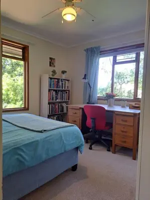 a bedroom with a bed and a desk and a chair at Helderberg Cottage in Somerset West