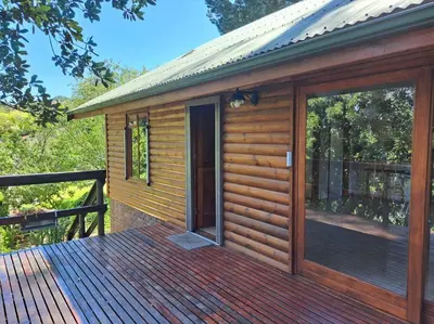 a wooden cabin with a large glass door on a deck at Helderberg Cottage in Somerset West