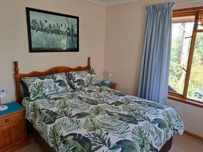 a bedroom with a bed with a green and white comforter at Helderberg Cottage in Somerset West