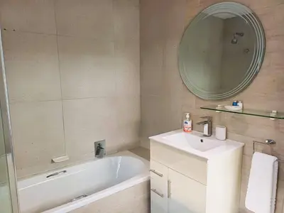 a bathroom with a tub and a sink and a mirror at 'Antilles'- 6 Bedroom Luxury Villa On The Beach, Sleeps 12 in Gordonʼs Bay