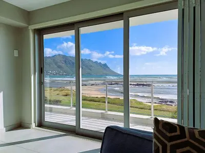 a room with a large window with a view of the beach at 'Antilles'- 6 Bedroom Luxury Villa On The Beach, Sleeps 12 in Gordonʼs Bay