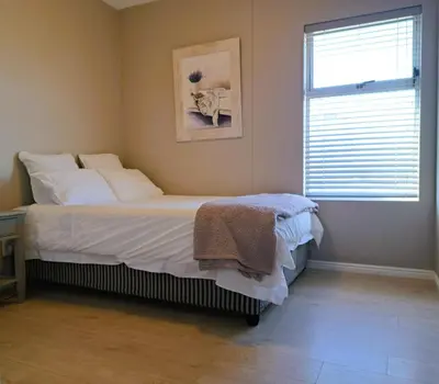 a bedroom with a bed with white sheets and a window at Cap d Azur beachfront apartment in Strand