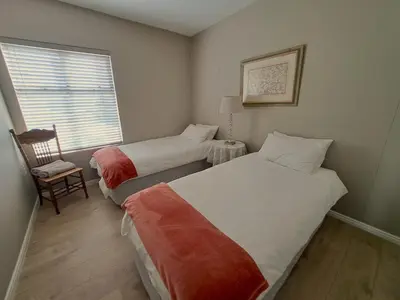 two beds in a room with a chair and a window at Cap d Azur beachfront apartment in Strand