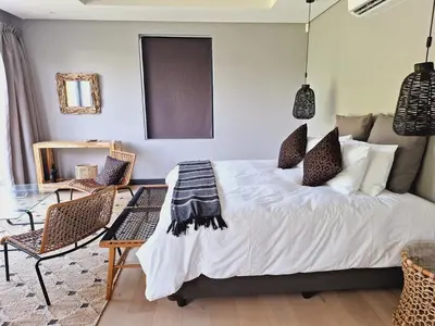 a bedroom with a bed with two chairs and a table at Drift Sunset Beach House in Sunset Beach