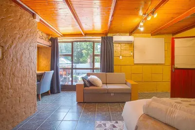 a room with a bed and a couch and a window at Suikerbos Guesthouse in Cape Town