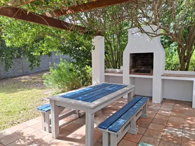 a picnic table and bench on a patio with a fireplace at Shonalanga (The setting sun) in Hermanus