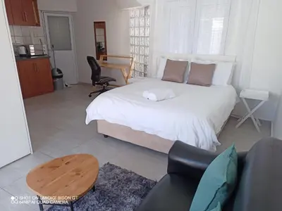 a bedroom with a bed and a table and a couch at Stay Palm 2 in Cape Town