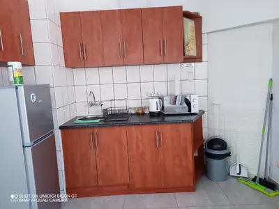 a small kitchen with wooden cabinets and a refrigerator at Stay Palm 2 in Cape Town