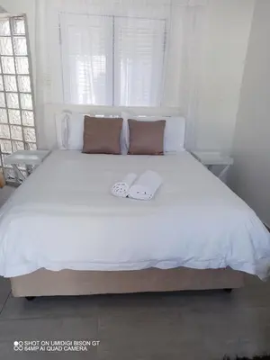 a white bed with two towels on top of it at Stay Palm 2 in Cape Town