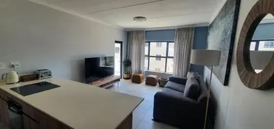 a kitchen and living room with a couch and a table at Luxury Beach Apartment in Cape Town