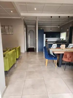 a living room with a table and some green chairs at Calmness in Claremont in Cape Town