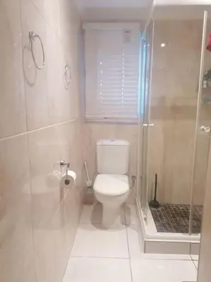 a bathroom with a toilet and a glass shower at Calmness in Claremont in Cape Town