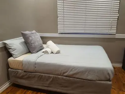 a bed sitting in a room with a window at Calmness in Claremont in Cape Town