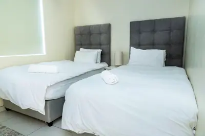 two beds in a room with white sheets at Sea Spray A308 in Bloubergstrand