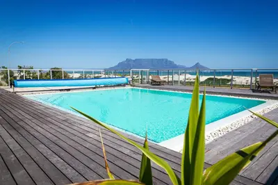 a swimming pool on a deck with a view of the ocean at Sea Spray A308 in Bloubergstrand