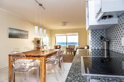 a kitchen and dining room with a table and chairs at Sea Spray A308 in Bloubergstrand