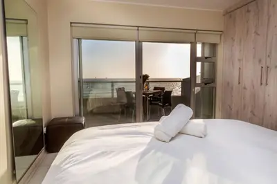 a bedroom with a bed with a view of a table at Sea Spray A308 in Bloubergstrand
