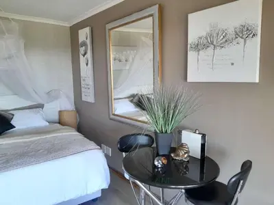 a bedroom with a bed and a table with a mirror at Roland’s Valley Art Accommodation in Stellenbosch