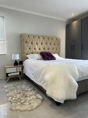 a bedroom with a large white bed with a furry rug at Urban Cosy City Haven in Cape Town