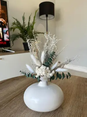 a white vase with flowers in it on a table at Urban Cosy City Haven in Cape Town