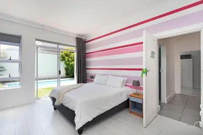 a bedroom with a bed with a striped wall at Sunset Westchester Villa in Cape Town