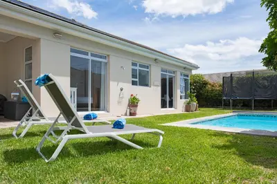 a lawn chair next to a swimming pool at Sunset Westchester Villa in Cape Town