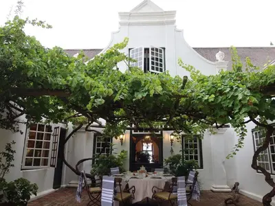 a dining table in the courtyard of a white house at Navarre Residence in Stellenbosch