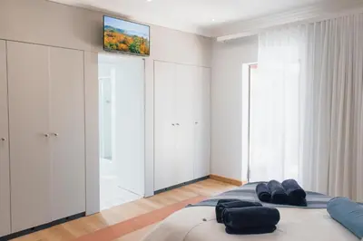 a bedroom with a bed with a tv on the wall at Tranquil Private Rooms Hermanus in Hermanus