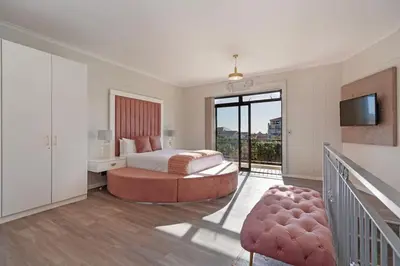a bedroom with a bed and a balcony with a television at Resort Style Penthouse - BackUp Power in Cape Town