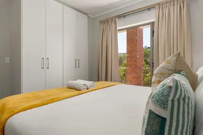 a bedroom with a bed with two rolled towels on it at Mayfair 219 in Cape Town