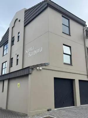 a building with a sign that reads smaller but shorter at Top Floor Executive apartment in Cape Town