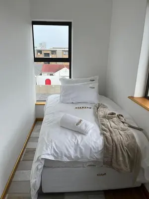 a white bed in a room with a window at Top Floor Executive apartment in Cape Town