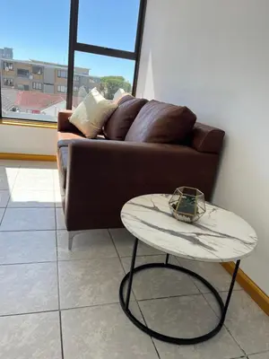 a brown couch in a living room with a table at Top Floor Executive apartment in Cape Town