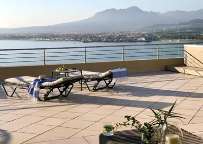 a balcony with a table and a view of the water at Bayview in Gordonʼs Bay
