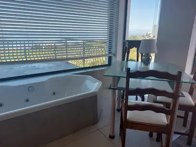 a bathroom with a tub and a table and a chair at The Waves of Schulphoek in Hermanus