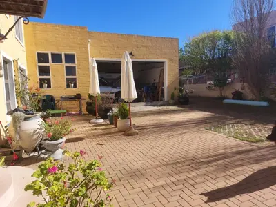 a patio with an umbrella and some potted plants at The Waves of Schulphoek in Hermanus