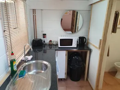 a kitchen with a sink and a microwave on a counter at The Red Fox in Cape Town