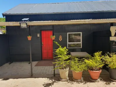 a black house with a red door and some plants at The Red Fox in Cape Town