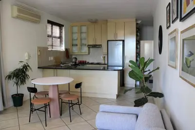 a kitchen and living room with a table and a couch at Contemporary Central Apartment by ARPA Hospitalities in Stellenbosch