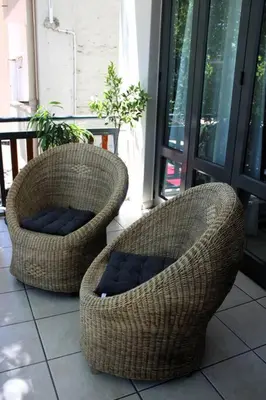 two wicker chairs sitting on a porch at Contemporary Central Apartment by ARPA Hospitalities in Stellenbosch